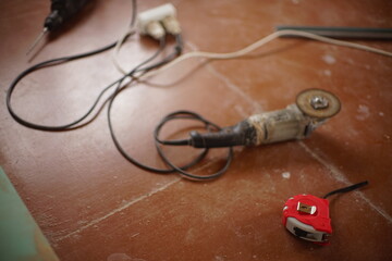 Red meter, grinding tool with abrasive cutting disc and other tools on the brown wooden floor
