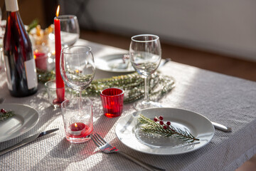 winter holidays, dinner party and celebration concept - christmas table serving with candles, crockery and wine at home