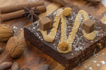 délicieux brownie au gâteau au chocolat avec noix, bâtons de cannelle et fèves de cacao sur planche de bois