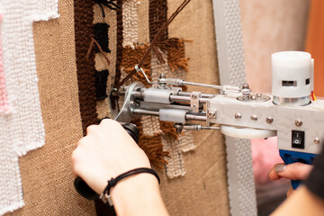 The process of making a small tank carpet using a tufting gun on burlap. - 472392690