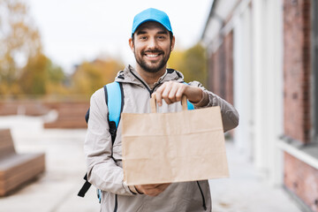 food shipping, profession and people concept - happy smiling delivery man with thermal insulated...
