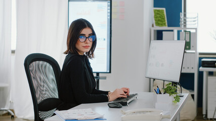 Portrait of businesswoman using computer for charts design at company office. Engineer with corporate job working with technology and monitor for data analysis, looking at camera.