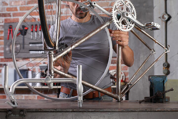man repair the vintage bicycle in garage workshop on the workbench with tools, diy concept - obrazy, fototapety, plakaty