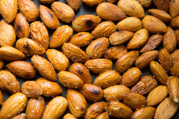 Filled frame background wallpaper shot of a bunch of crunchy roasted almonds with sea salt on a...