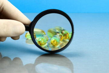 Capsules of Omega 3 vitamins fish oil through a magnifying glass. Selective focus