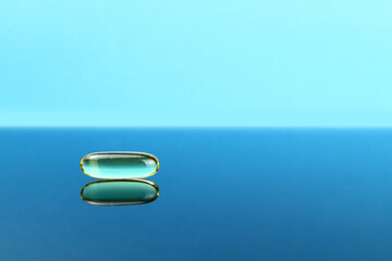 omega 3 capsule on mirror surface. Space for text