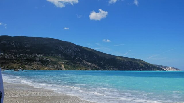 Charming Woman With Smartphone In Hand Walking Away From The Shore Smiling In Agia Kiriaki Beach, Zola In Kefalonia, Greece. - Medium Shot