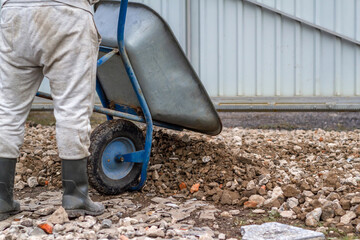 A man is driving a cart with rubble. Distribution of rubble on the road. Concept: construction, road repairs, sale of crushed stone, backgrounds and textures, working tools.