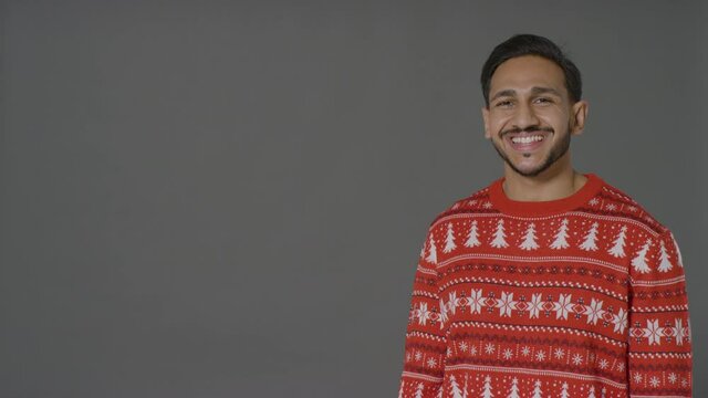 Portrait Shot of Young Man In Christmas Sweater Saying Merry Christmas with Copy Space