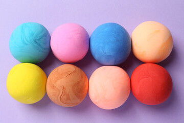 Different color play dough on violet background, flat lay