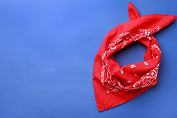Folded red bandana with paisley pattern on blue background, top view. Space for text