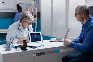 Medic and patient analyzing illustration of human body on digital tablet, to explain medical diagnosis. General practitioner and man looking at anatomical analysis on gadget for healthcare