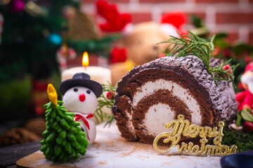 Chocolate yule log cake with snowman and santa clause made from sugar on wooden table for celebrate...