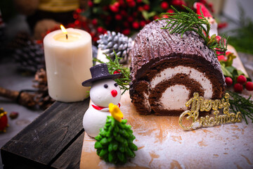 Chocolate yule log cake with snowman and santa clause made from sugar on wooden table for celebrate in christmas and new year festival.
