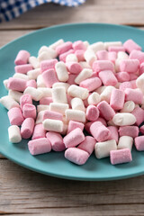 Sweet marshmallows topping in a blue plate on wooden table