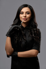 Experienced dermatologist in black uniform and gloves standing in studio with syringe in hands. Concept of cosmetology and injection procedures for skin care.