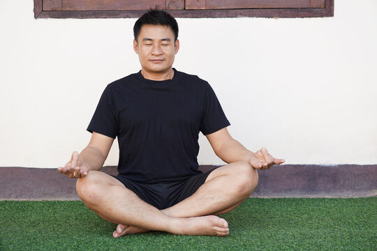 Asian Middle Aged Man Sits And Do Yoga Meditation In Green Floor At Home. Concept : Health Care. Sport Healthy Life. Feels Calm And    Relax After Work Or Busy Day. 