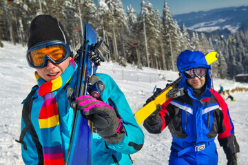 Skiers holding skies; blue jacket;  horizontal orientation - obrazy, fototapety, plakaty