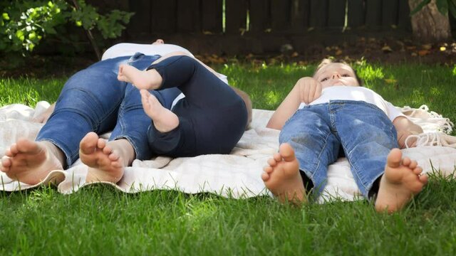 Closeup of children and mothers feet lying on grass in park or garden. Parenting, family, children development, and fun outdoors in nature.