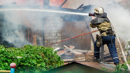 Kamianske, Ukraine - July 08, 2011: firefighter extinguishes a burning building with water, rescue...