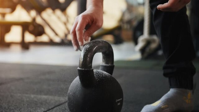 Close up view of hands of man that cleaning black dumbbell in gym