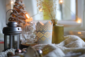 Various Christmas decorations in neutral colors, soft knitted blanket and lit candles. Selective...