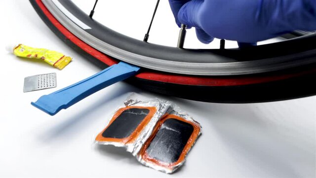 A person repairs a puncture of a bicycle wheel, using cycling repair tools, video on white background