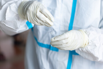 The doctor with PPE suit, Doctor is using a test coronavirus(covid-19) with the use of an ATK test kit by nasal swab.
