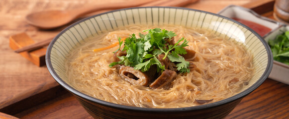 Delicious intestine vermicelli in a bowl on dark wooden table background.