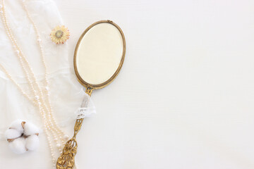 Background of white delicate lace fabric, pearls and vintage hand mirror