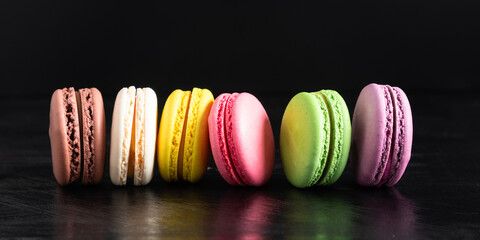 Colorful cake macaron or macaroon on black background. Flat lay, top view, copy space