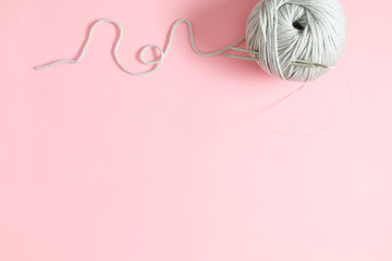 Knitting needles and yarn on pink background. Yarn for knitting. Needlework background. Flat lay, top view, copy space