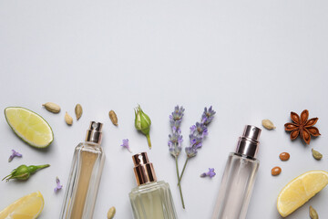 Flat lay composition with bottles of perfume, citrus fruits and flowers on light grey background....