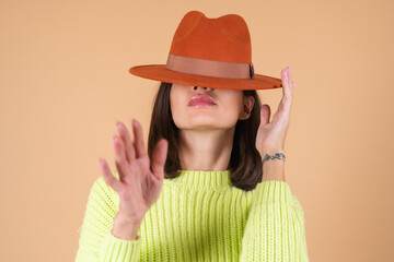 Fashionable stylish woman on beige background in sweater and hat posing