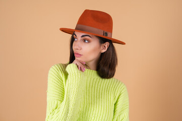 Fashionable stylish woman on beige background in sweater and hat posing