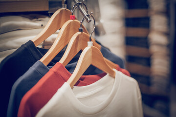 T-shirts on hangers. Stacks of clothes. Shopping in store. Clothes on hangers in shop for sale - 472410292