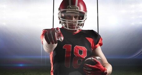 Portrait of confident male player holding ball challenging you for american football match