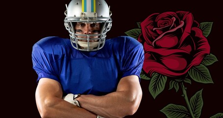Portrait of confident male american footballer with arms crossed by rose against black background