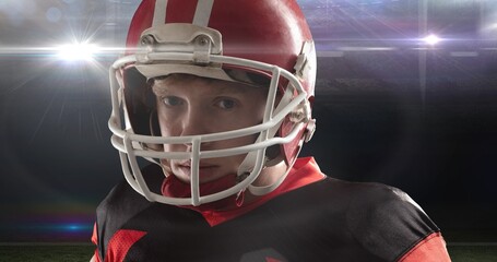 Fototapeta na wymiar Portrait of young male american footballer wearing red helmet at illuminated stadium