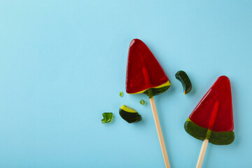 Red lollipop candy broken in pieces on blue background