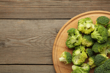 Bunch of fresh green broccoli on cutting board on grey wooden background.