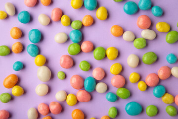 Fototapeta na wymiar Colorful chocolate candy pills on purple background.