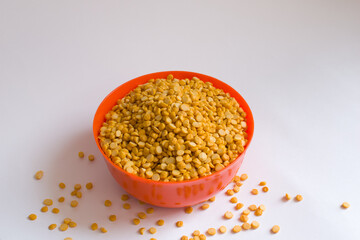 Yellow split peas in an orange bowl in isolated white background
