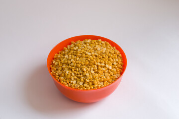Yellow split peas in an orange bowl in isolated white background.