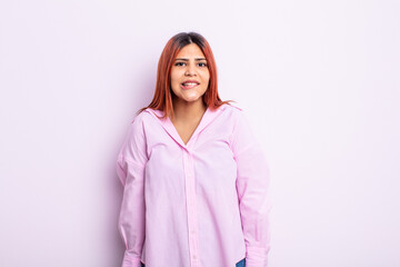 young hispanic woman looking puzzled and confused, biting lip with a nervous gesture, not knowing...