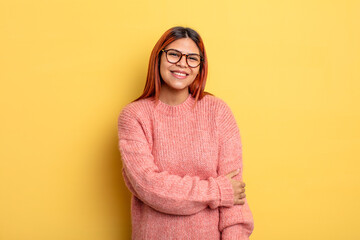 young hispanic woman laughing shyly and cheerfully, with a friendly and positive but insecure...