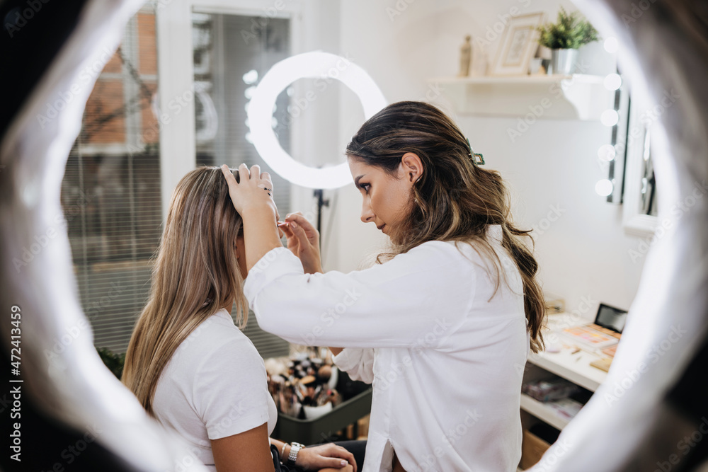 Wall mural makeup process. professional artist applying make up on model face. portrait of beautiful blonde wom