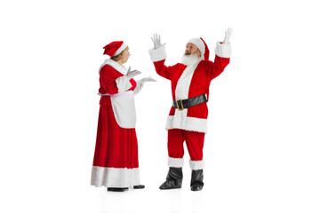 Excited senior man and beautiful woman, Santa Claus and missis Claus in traditional New Year costume isolated on white background.