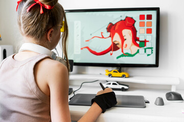 A young girl draws on a PC using a graphics tablet in her comfortable home office.