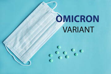 Medical protective mask and pills in capsules on a blue background with B.1.1.529 omicron variant...